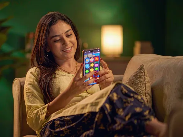 tr2026 Woman smiling at a smartphone showing a colourful slot game