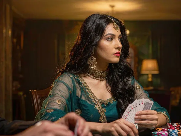 tr2026 Woman in teal and gold holding cards at a poker table with chips