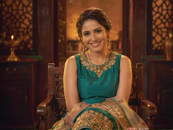 tr2026 Woman in a teal and gold kameez smiling at three face-up cards