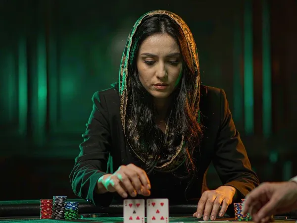 tr2026 Woman concentrating on two face-up cards at a blackjack table with chips