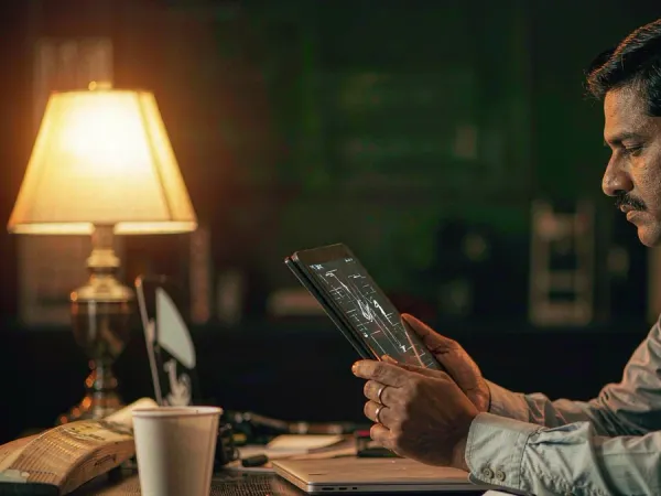 tr2026 Man studying a tablet beside a cricket bat and coffee cup