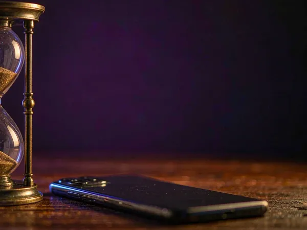 tr2026 Hourglass beside a smartphone on a wooden table